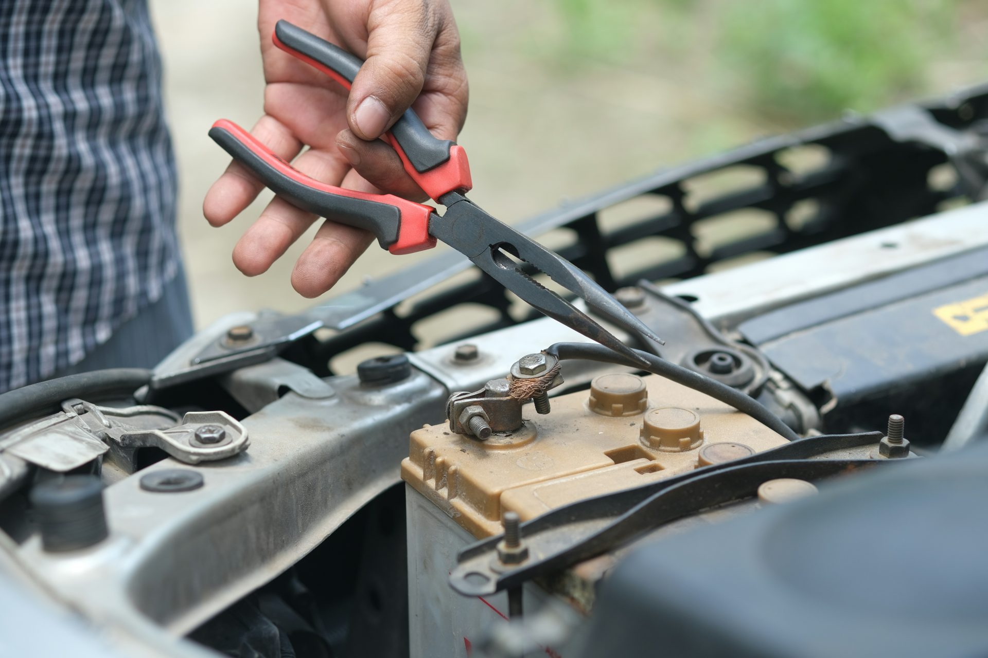 Mechanic examining car's undercarriage at a garage, focusing on vehicle maintenance.